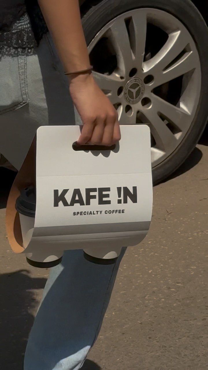 A white KAFE !N paper bag held by the handle