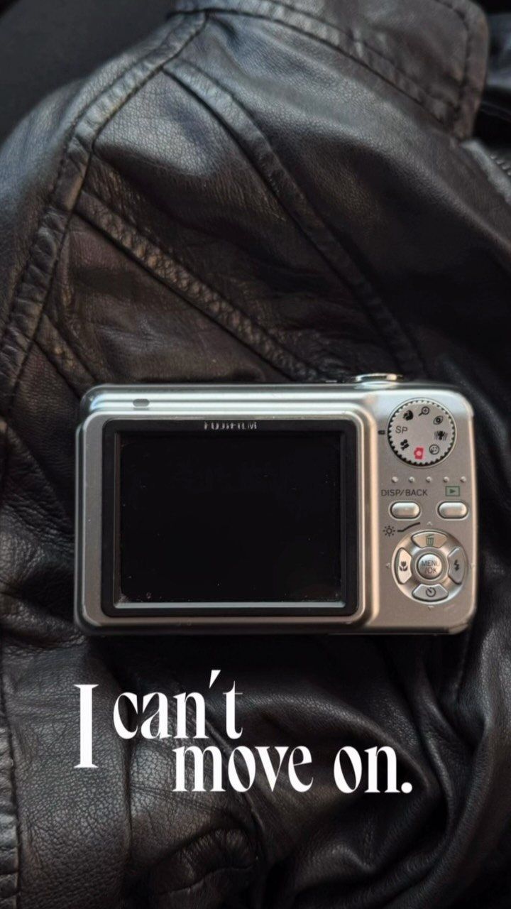 An old silver digital camera on a black leather jacket