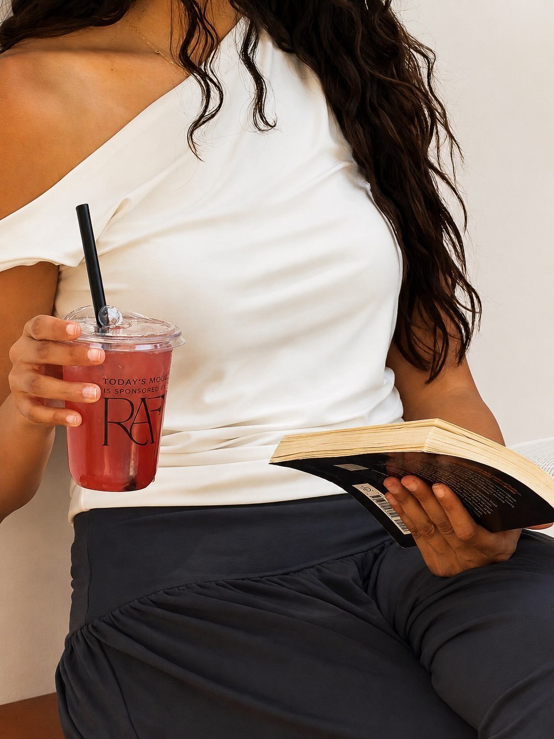 A woman reading with a red iced drink in a RAF cup